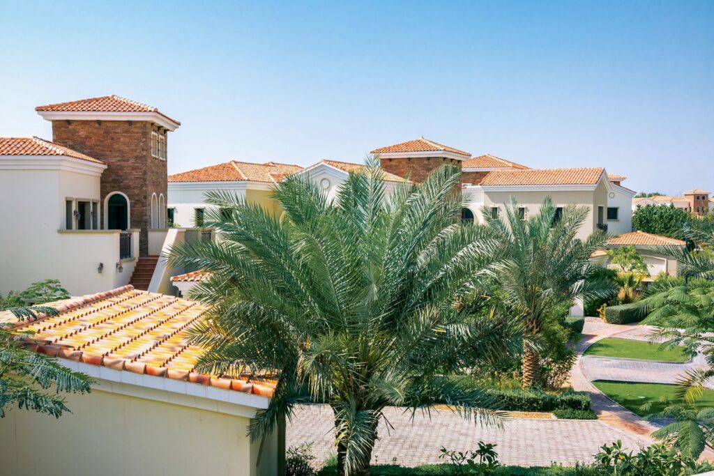 Elegant Mediterranean villas with red tile roofs surrounded by lush palm trees.